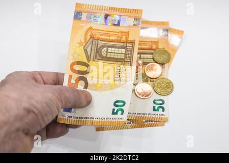 Männlicher Zeiger mit 50-Euro-Note und Münzen im Hintergrund Stockfoto