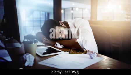 Hes nannte es eine Nacht. Eine kurze Aufnahme eines hübschen jungen Mannes, der an seinem Schreibtisch schläft, während er spät im Büro arbeitet. Stockfoto