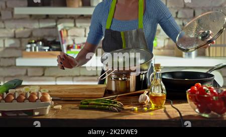 Eine gesichtslose Frau, die in der Küche kocht Stockfoto