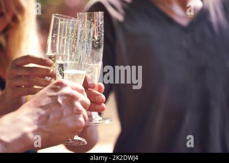 Flüssiges Funkeln. Ein kurzer Schuss von Leuten, die zusammen Champagner trinken, in einer Außenumgebung. Stockfoto