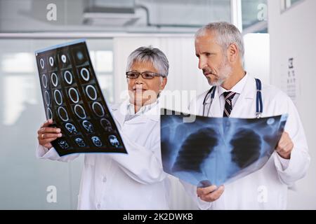 Gemeinsam eine Diagnose identifizieren. Ausgeschnittene Aufnahme von zwei Ärzten, die Röntgenbilder zusammen betrachten. Stockfoto