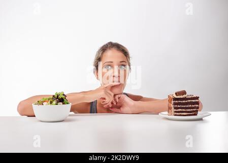 Shes ein Liebhaber von Schokolade. Studioaufnahme einer attraktiven jungen Frau, die von etwas Süßem verlockt wird. Stockfoto