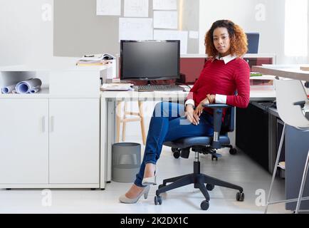 Shes immer die letzte in der ofce. Porträt einer jungen Designerin, die an ihrem Arbeitsplatz in einem Büro sitzt. Stockfoto