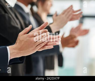 Ein weiteres schönes Seminar in den Büchern. Nahaufnahme einer Gruppe von Führungskräften, die klatschten, während sie in einer Reihe in einem Büro standen. Stockfoto