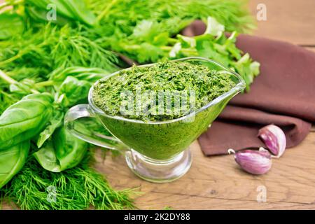 Soße aus würzigem Grün in einem Sauce-Boot auf einem alten Holzbrett Stockfoto