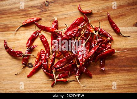 Zeit, die Hitze aufzuheizen. Eine Aufnahme frischer roter Chilischoten aus einem hohen Winkel auf einer Küchentischfläche. Stockfoto