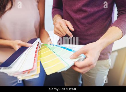 Die perfekte Farbe finden. Freigestellte Aufnahme von zwei unverkennbaren Designern, die ein Farbmuster betrachten. Stockfoto