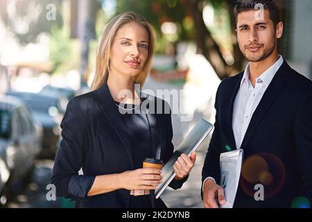 Dynamische Partnerschaft, die auf Professionalität basiert. Portrait von zwei selbstbewussten Kollegen, die draußen zusammen stehen. Stockfoto