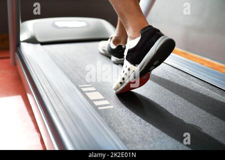 Laufen, um fit zu bleiben. Nahaufnahme eines Mannes auf einem Laufband im Fitnessstudio. Stockfoto