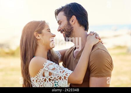 Sie haben nur Augen füreinander. Aufnahme eines lächelnden jungen Paares, das sich umarmt, während er einen Tag gemeinsam im Park genießt. Stockfoto