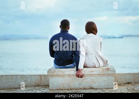 Entspannen mit der perfekten Aussicht. Rückansicht eines jungen Paares mit Blick auf das Meer im Freien. Stockfoto