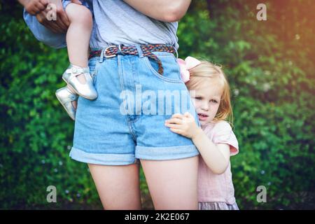 Probleme beim Loslassen. Aufnahme eines kleinen Mädchens, das während eines Tages im Freien an ihrer Mutter festhält. Stockfoto