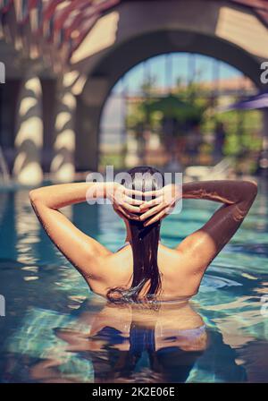 Nur ein weiterer Tag im Paradies. Aufnahme einer jungen Frau, die sich in einem Spa im Pool entspannen kann. Stockfoto