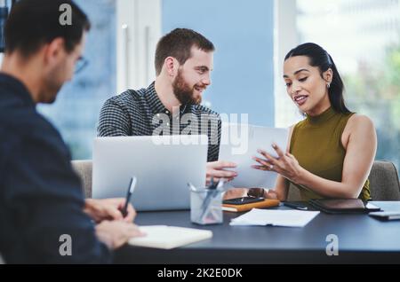 Umsetzung ihrer Pläne bis ins Detail. Aufnahme einer Gruppe junger Designer, die in einem Büro diskutieren. Stockfoto