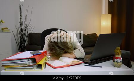 Müde, gestresste, überarbeitete Geschäftsfrau, die am Schreibtisch eingeschlafen ist Stockfoto