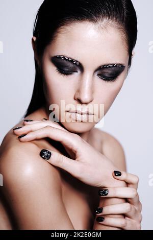 Intensive Schönheit. Studioaufnahme einer schönen jungen Frau, die ein metallisches Make-up und einen Nagellack trägt. Stockfoto