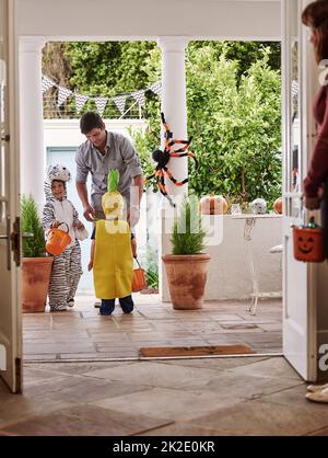 Sie sind bereit, Tricks oder Behandlungen zu machen. In voller Länge Aufnahme von zwei entzückenden kleinen Jungen, die Halloween mit ihren Eltern zu Hause feiern. Stockfoto