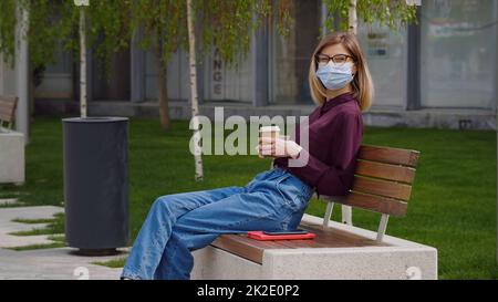 Park Frau liest Buch auf der Werkbank lächelt glücklich an der Kamera. Hübsche junge multikulturelle Frau genießen Frühling im Park. Stockfoto