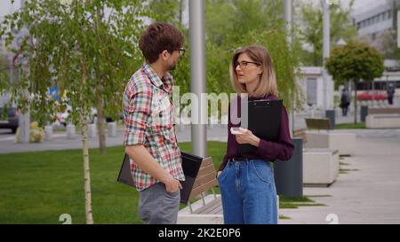 Zwei Studenten, die sich auf dem Campus treffen und unterhalten, in einem Park. Stockfoto
