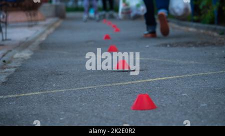 Kinder Schlittschuhe auf Asphalt und geht um Kegel Stockfoto