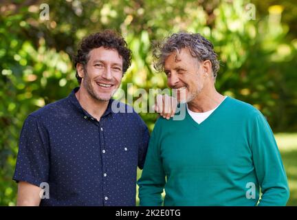 Das Erbe leben. Porträt eines jungen Mannes und seines älteren Vaters, die im Freien zusammen stehen. Stockfoto