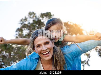 Ihre Mutter ist ihre größte Unterstützerin. Porträt einer glücklichen Mutter und Tochter, die eine Huckepack-Fahrt im Freien genießen. Stockfoto