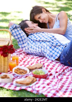 Perfektes Picknick. Ein glückliches junges Paar genießt ein Picknick in der Sommersonne. Stockfoto