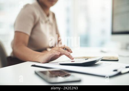 Arbeiten an ihren Geschäftseinnahmen und -Ausgaben. Nahaufnahme einer unkenntlichen Geschäftsfrau, die in einem Büro die Finanzen berechnet. Stockfoto