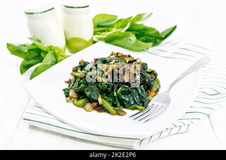 Mit Zwiebeln gebratener Spinat auf dem Teller auf dem Light Board Stockfoto