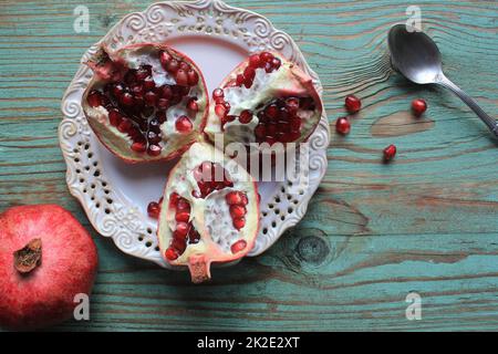 Granatäpfel auf weißem Teller mit Löffel. Blauer Hintergrund . . Stockfoto