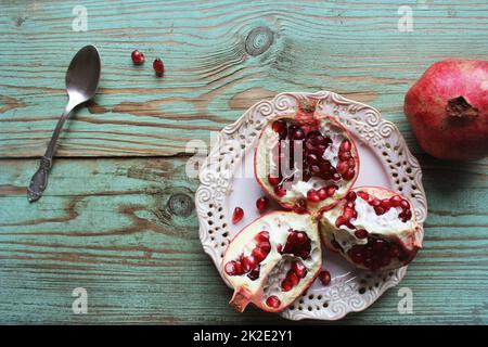 Granatäpfel auf weißem Teller mit Löffel. Blauer Hintergrund . . Stockfoto