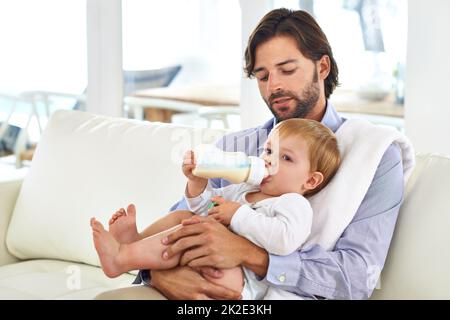 Sein Baby füttern. Beschnittene Ansicht eines Vaters, der seinem jungen Sohn eine Flasche gab. Stockfoto