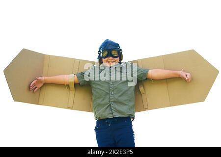 Seine Fantasie ist hoch im Anflug. Aufnahme eines verspielten kleinen Jungen, der vorgibt, ein Flugzeug mit einem Paar Flügel aus Pappe zu sein. Stockfoto