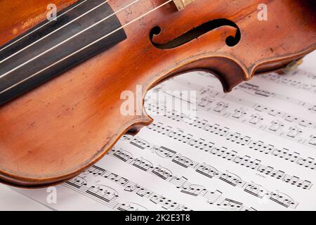 Lass die Musik beginnen. Zugeschnittenes Bild einer Geige, die auf Notenblättern liegt. Stockfoto