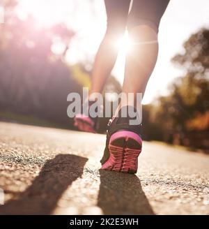 Auf lange Sicht in der IT. Kurze Aufnahme einer Frau, die sich für einen Lauf die Beine ausstreckt. Stockfoto