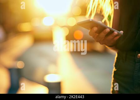 Treffen Sie mich in der Stadt. Ausgeschnittene Aufnahme einer nicht erkennbaren jungen Frau, die einen Text sendet, während sie durch die Stadt läuft. Stockfoto