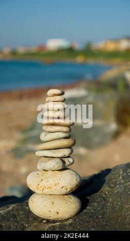 Balancierte Steinpyramide auf Sand am Strand. Stockfoto