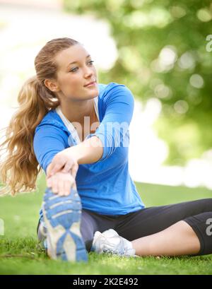 Dehnung ist entscheidend. Attraktiver junger Läufer, der sich vor einem Lauf dehnt. Stockfoto