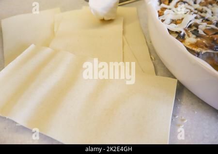 Traditionelle hausgemachte Lasagne. Lasagne-Platten IN DER NÄHE Einer RUNDEN KERAMIK-BACKFORM, Draufsicht Stockfoto