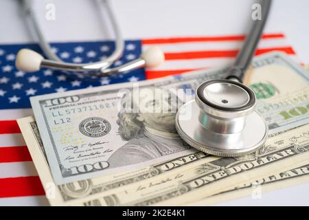 Schwarzes Stethoskop mit US-Dollar-Banknoten auf US-amerikanischer Flagge, Geschäfts- und Finanzkonzept. Stockfoto