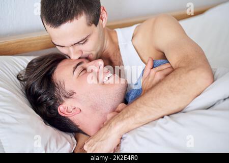 Ein junges schwules Paar, das sich im Bett entspannt.