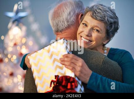 Weihnachtsumarmungen sind ihr eigenes Geschenk. Aufnahme einer reifen Frau, die ihren Partner umarmt, um ihm für ihr Geschenk zu danken. Stockfoto