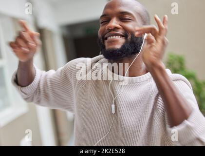 Tanzpausen sind unerlässlich. Aufnahme eines jungen Mannes, der zu Hause tanzt und Musik hört. Stockfoto