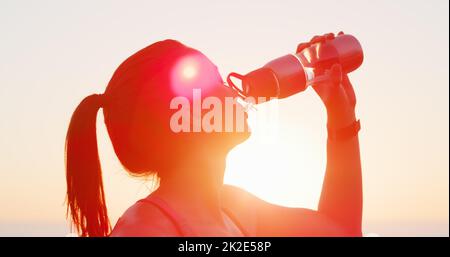 Wasser ist Ihr bester Fitness-Kumpel. Kurzer Schuss einer attraktiven jungen Frau, die beim draußen-Arbeiten Wasser trinkt. Stockfoto