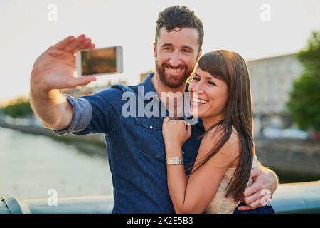 Ihre Liebe festhalten. Ausgeschnittene Aufnahme eines anhänglichen jungen Paares, das Selfies macht, während es ein Date hat. Stockfoto