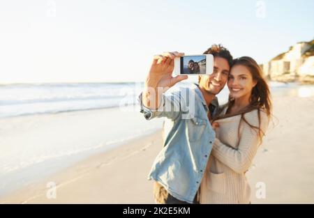 Liebe am Strand. Aufnahme eines liebevollen jungen Paares, das am Strand ein Selfie gemacht hat. Stockfoto