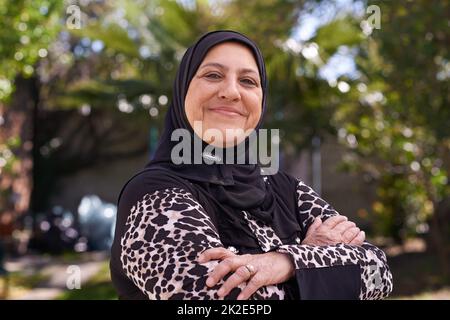 Sie liebt ihr Erbe. Porträt einer reifen muslimischen Frau, die draußen steht. Stockfoto