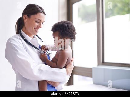 Nur für eine routinemäßige pädiatrische Untersuchung. Eine kurze Aufnahme einer Kinderärztin, die eine Untersuchung eines entzückenden Jungen macht. Stockfoto