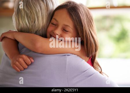 Oma eine große Umarmung geben. Aufnahme eines niedlichen kleinen Mädchens, das ihre Großmutter umarmt. Stockfoto