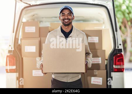 Für eine weitere Lieferung wird angehalten. Porträt eines Lieferers, der Kisten aus seinem Lieferwagen auslädt. Stockfoto